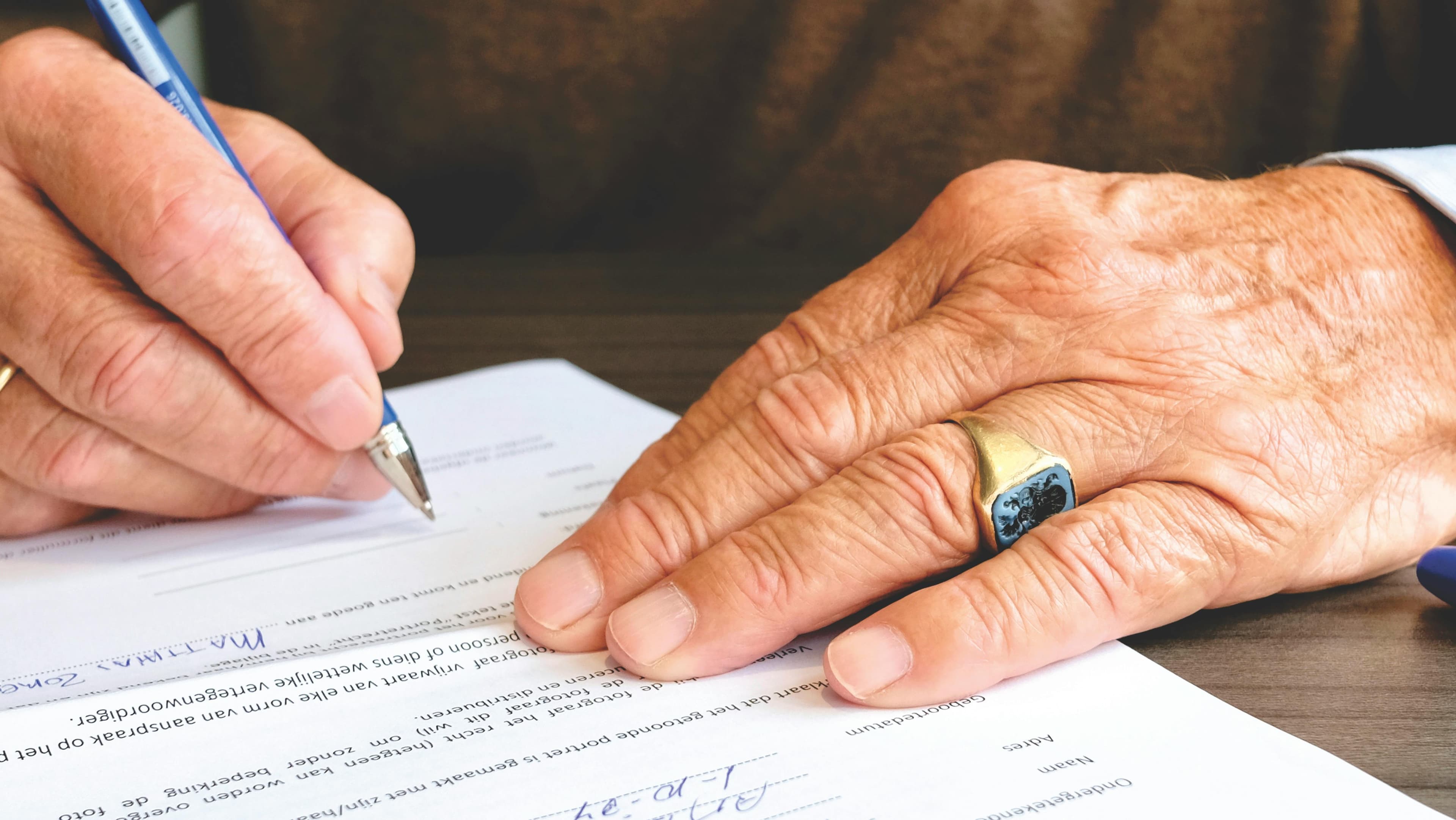 Senior hand signing a will and estate document