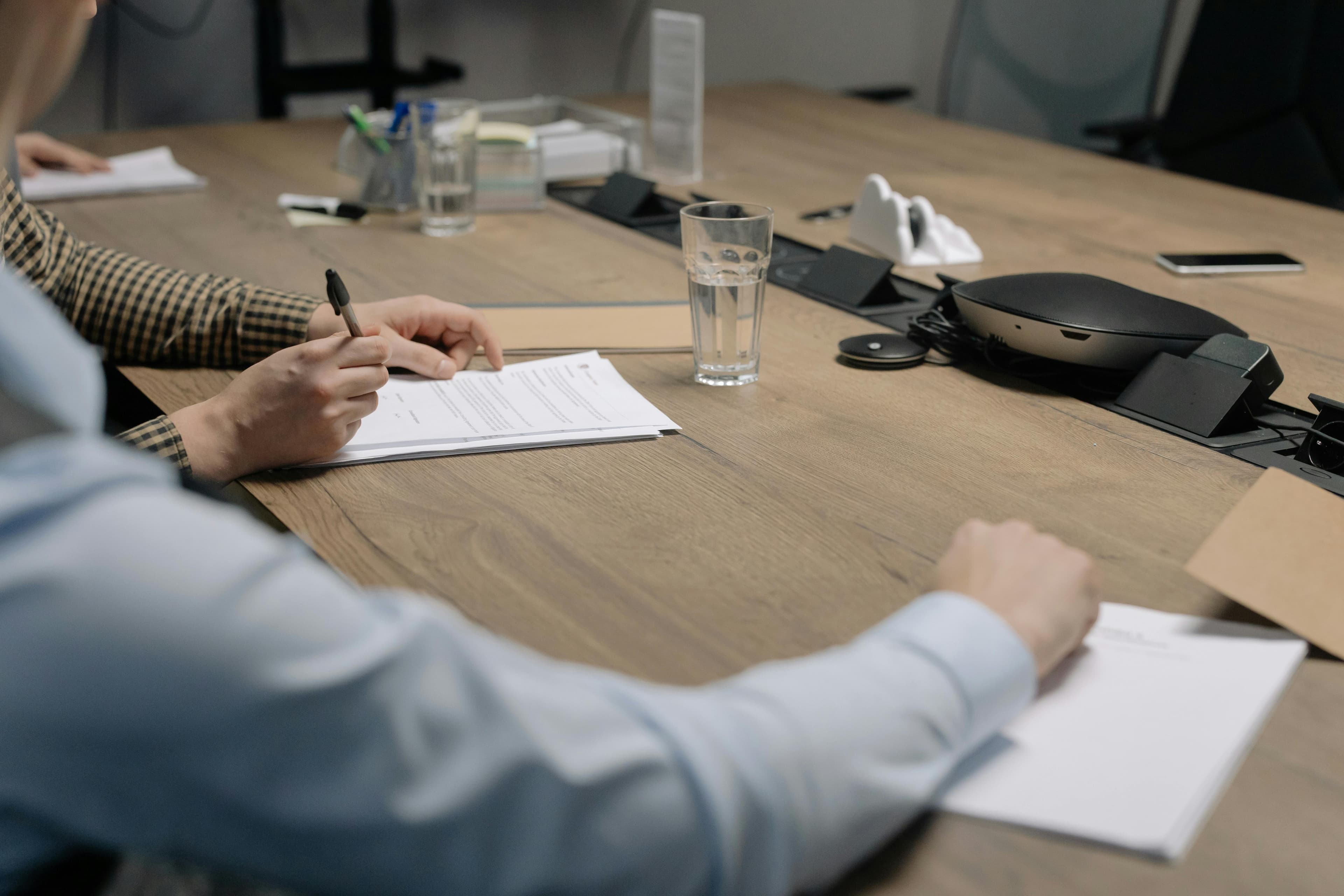 Business owners signing a sale agreement around a conference table